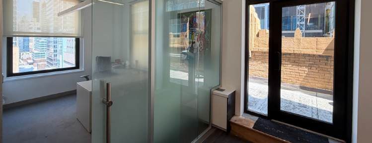 Glass-partitioned office beside a pair of black-framed glass doors